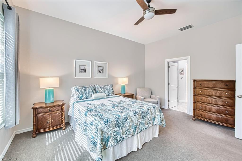 Carpeted bedroom featuring a ceiling fan and ensuite bathroom