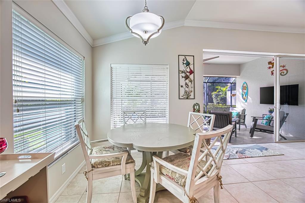 Dining area with vaulted ceiling, crown molding, and light tile patterned floors