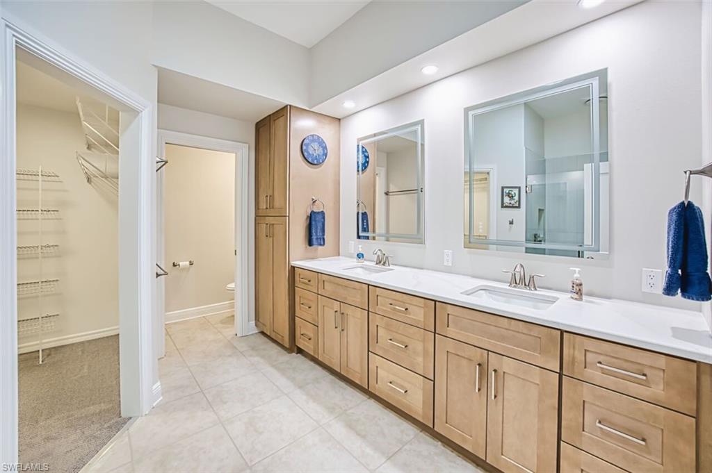 Full bathroom featuring a walk in closet, double vanity, light tile patterned flooring, light carpet, and recessed lighting