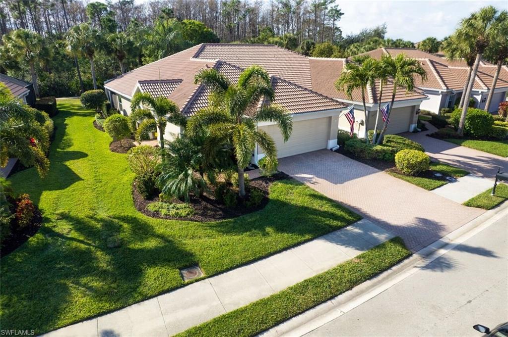View of front of house with a front yard, decorative driveway, a tile roof, a garage, and stucco siding