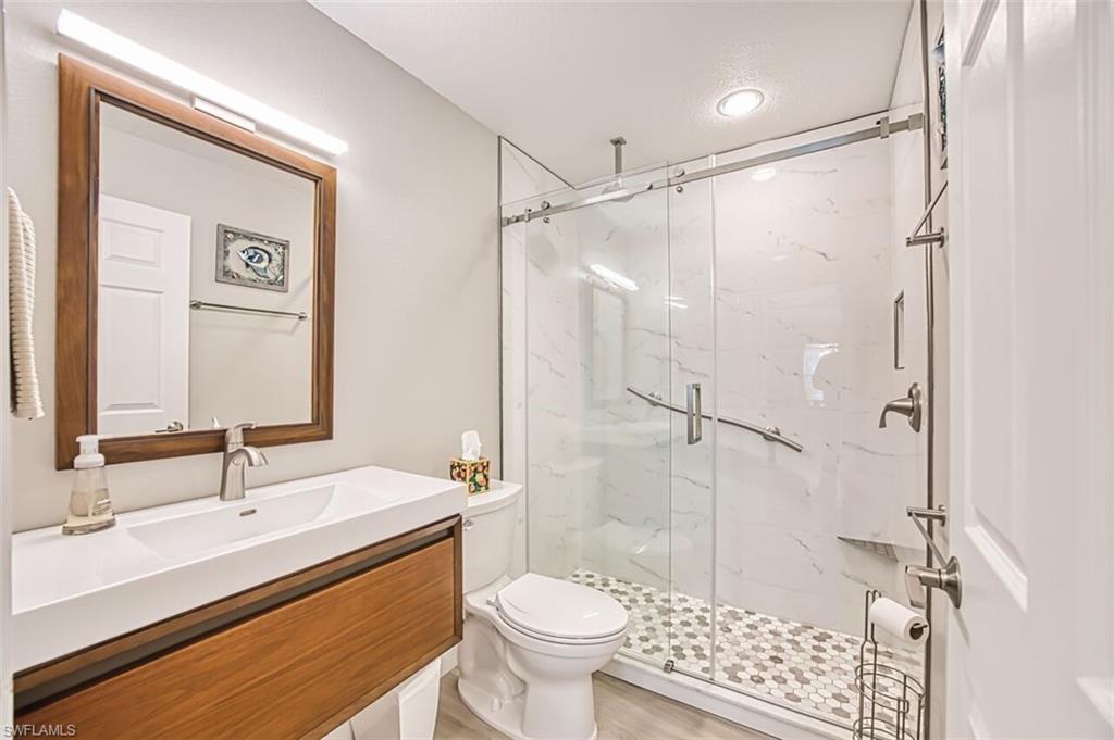 Bathroom featuring vanity, a marble finish shower, and light wood finished floors