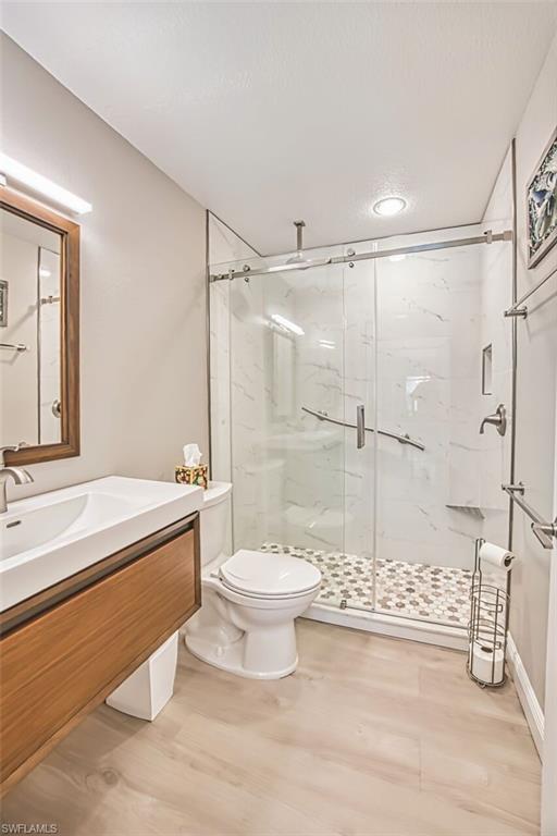 Full bathroom featuring vanity, a marble finish shower, and light wood-type flooring
