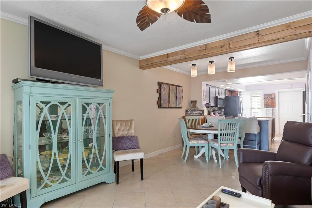 Living room featuring ornamental molding, light tile patterned floors, and ceiling fan