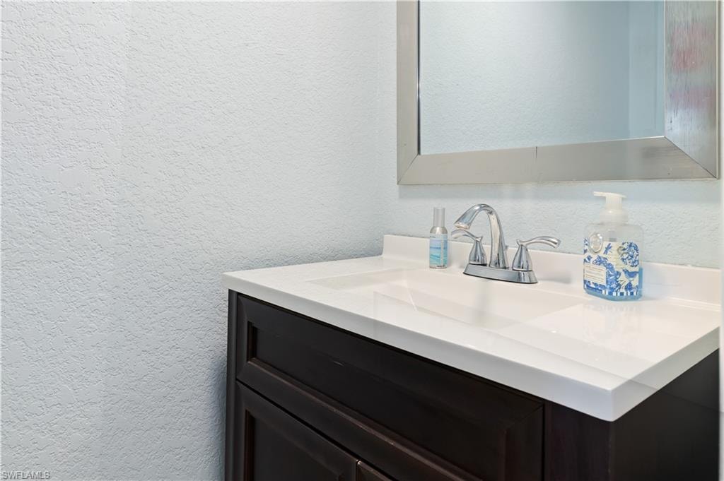 Bathroom with a textured wall and vanity
