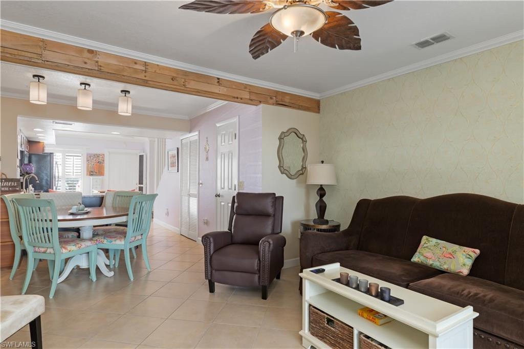 Living area featuring crown molding, ceiling fan, light tile patterned flooring, and wallpapered walls