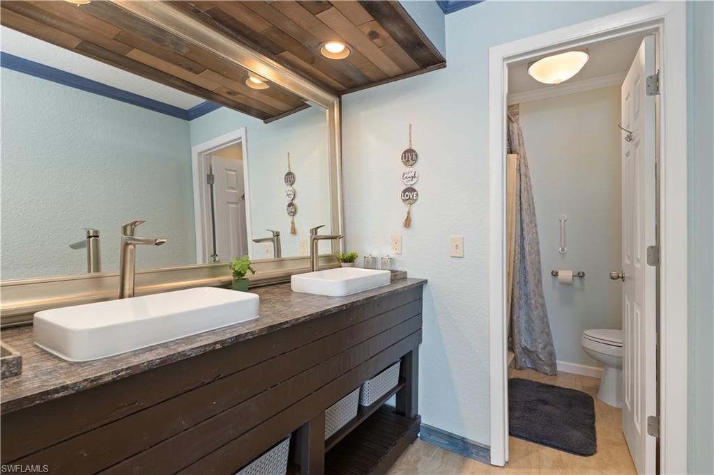 Full bath featuring double vanity, a textured wall, ornamental molding, and recessed lighting