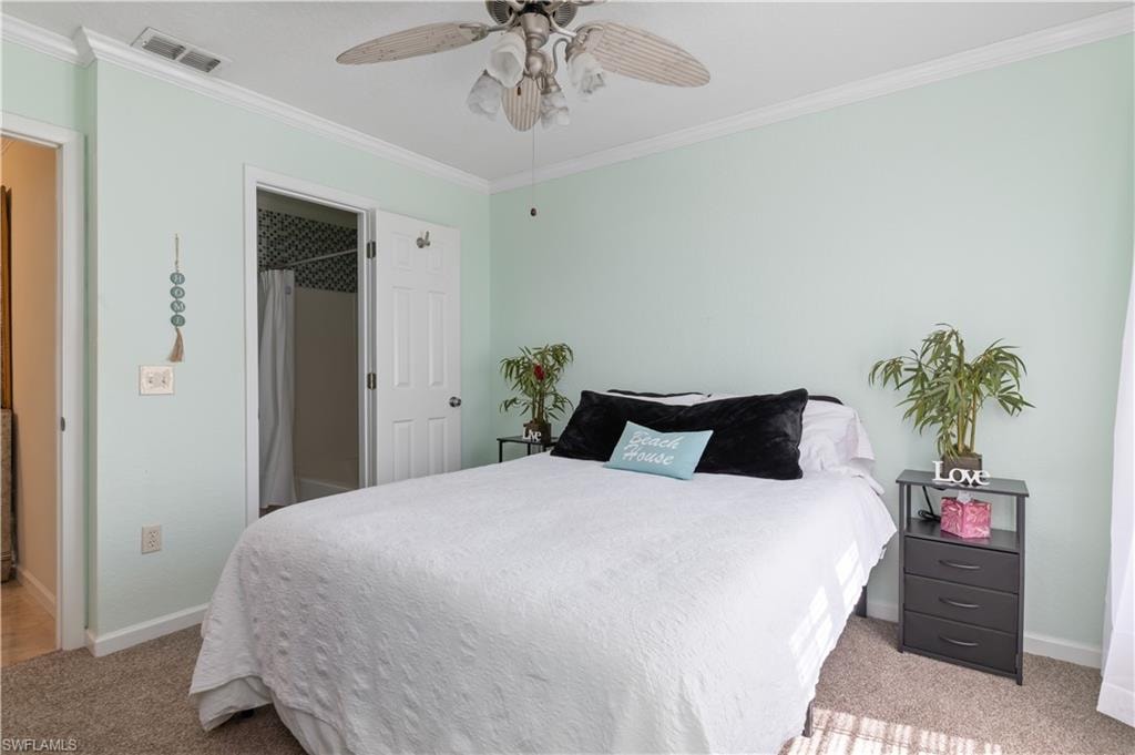 Bedroom with crown molding, light colored carpet, and a ceiling fan