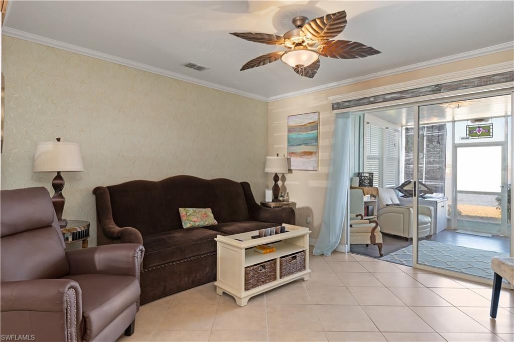 Living room featuring ornamental molding, ceiling fan, light tile patterned floors, and wallpapered walls