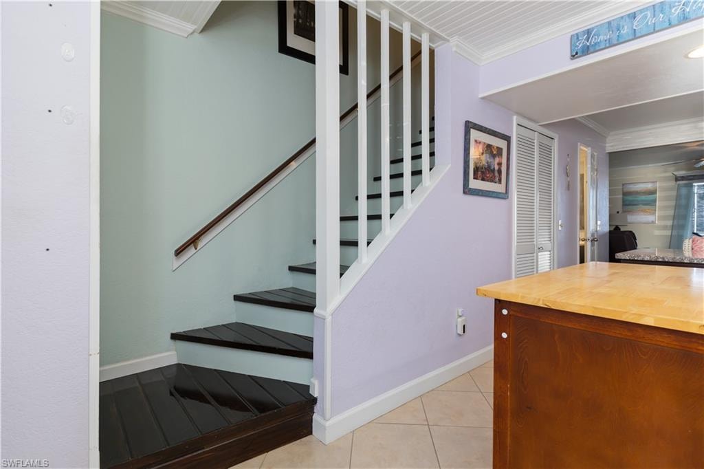 Stairs featuring crown molding and tile patterned floors