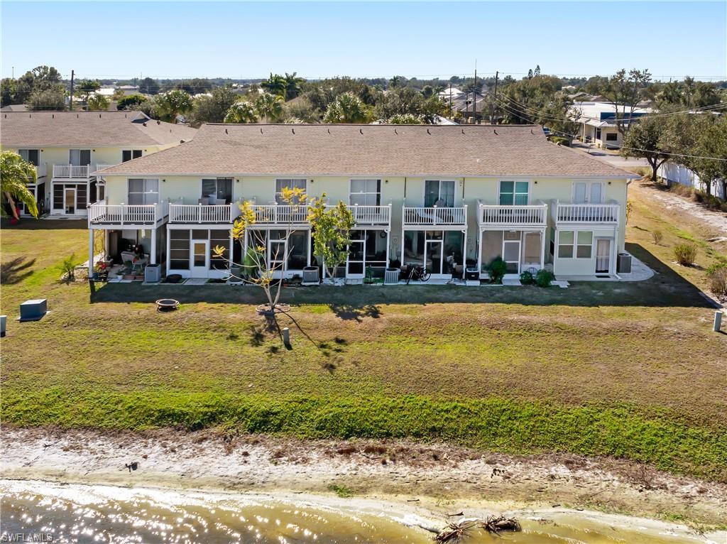 Back of property with a patio area, a lawn, a balcony, and roof with shingles