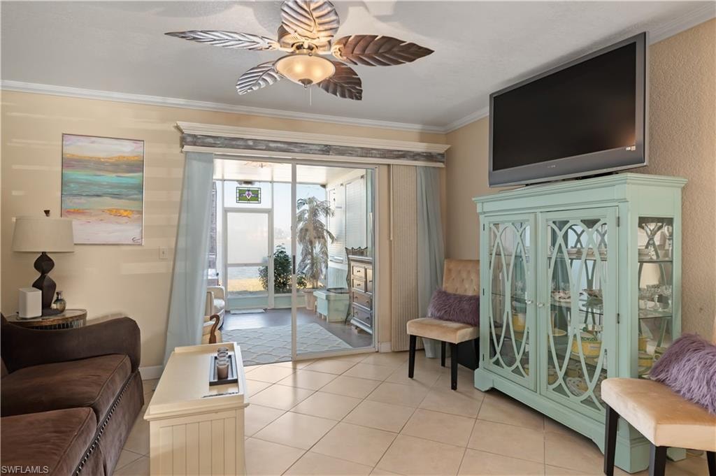 Living room featuring crown molding, a ceiling fan, and light tile patterned floors