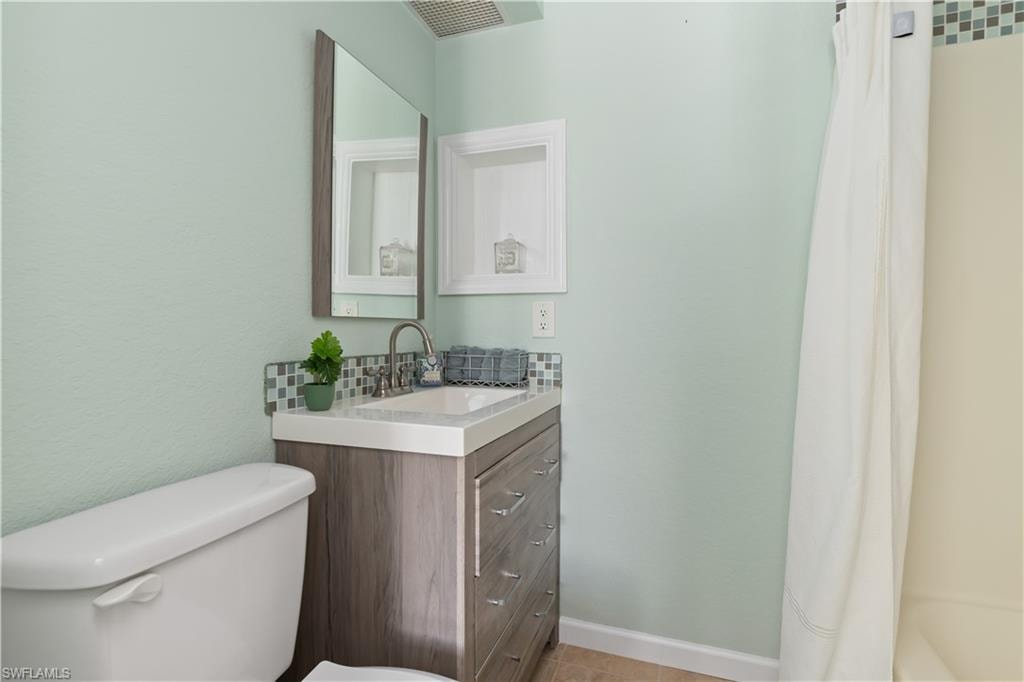 Full bathroom featuring vanity, shower / bath combo with shower curtain, and a textured wall