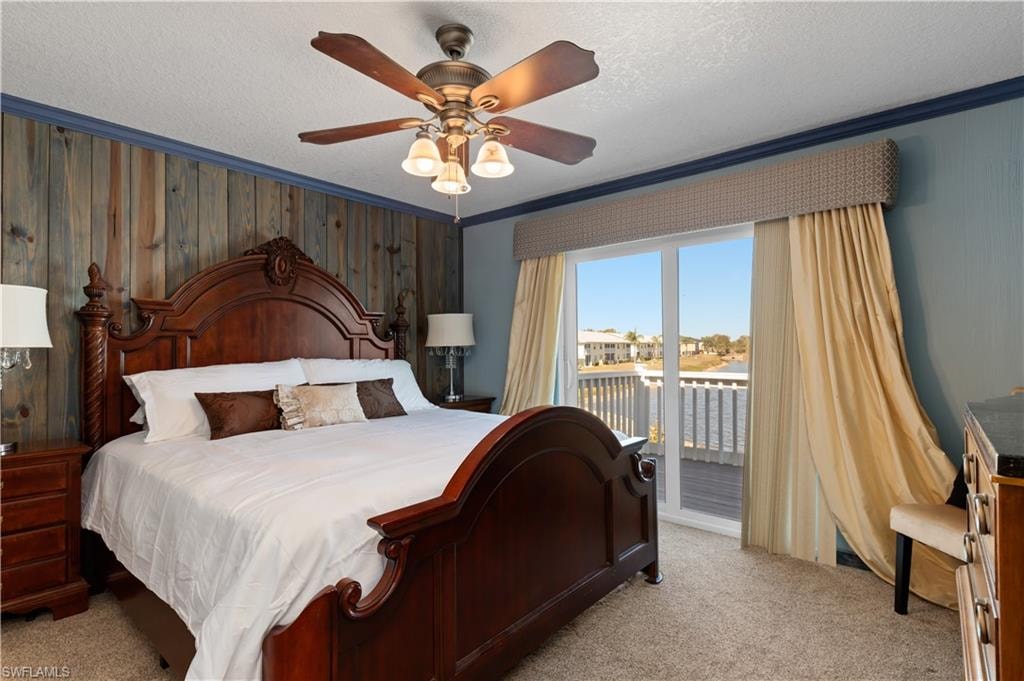 Bedroom featuring wood walls, access to outside, carpet flooring, a textured ceiling, and a ceiling fan