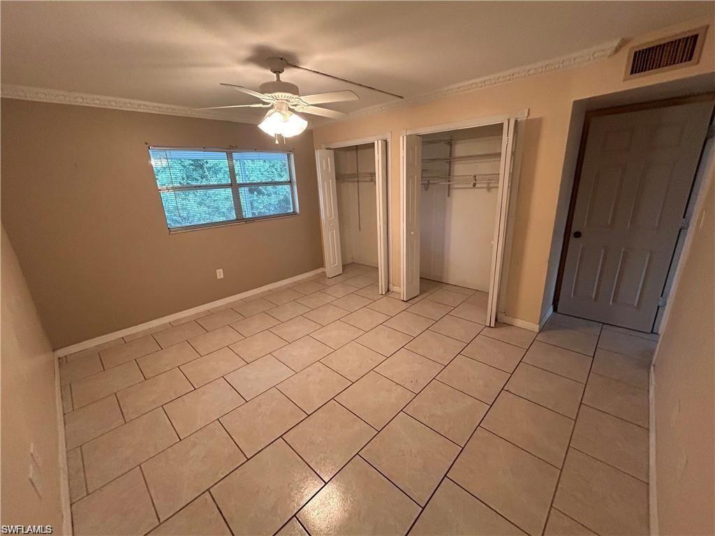 Unfurnished bedroom with two closets, ceiling fan, and light tile patterned floors