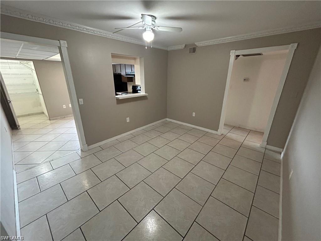 Empty room featuring a ceiling fan, light tile patterned floors, and ornamental molding
