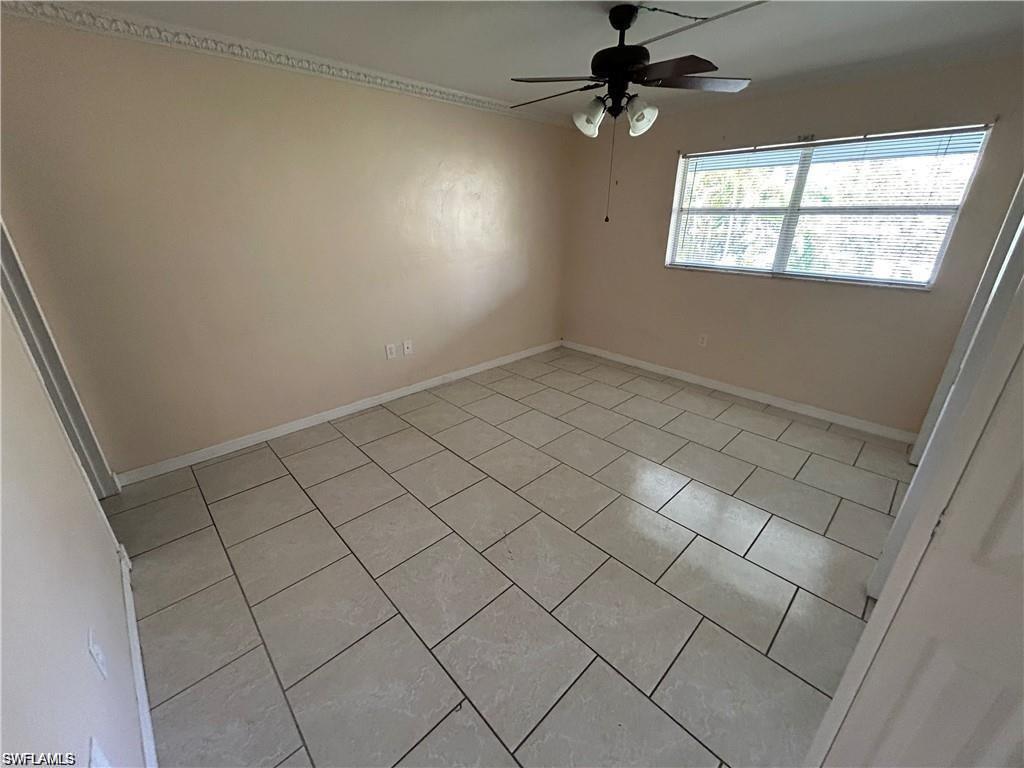 Empty room with a ceiling fan and light tile patterned floors
