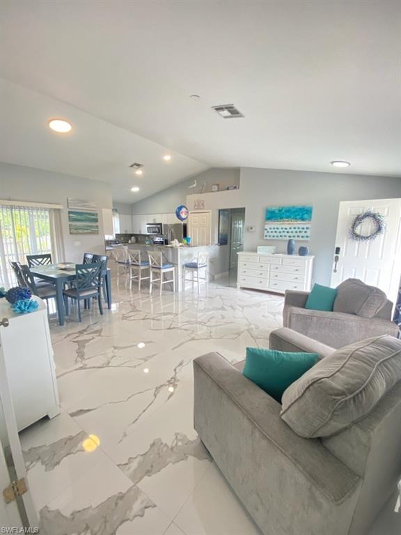 Living room with lofted ceiling, recessed lighting, and light marble finish floors