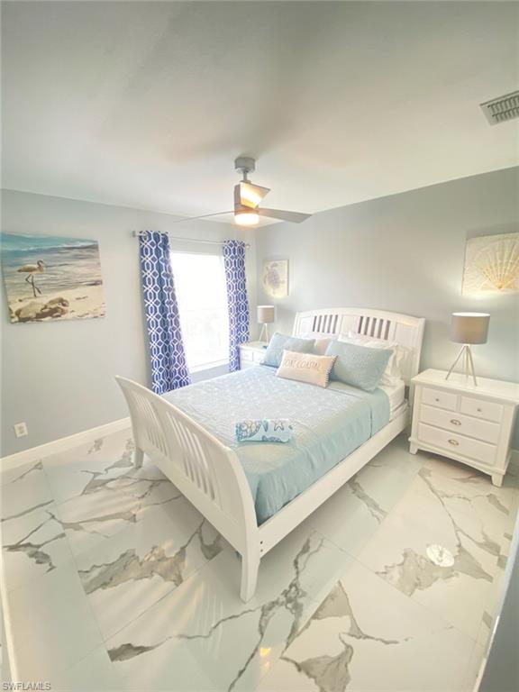 Bedroom featuring ceiling fan and marble finish floors