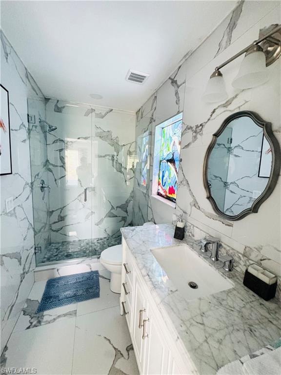 Bathroom with vanity, a marble finish shower, stone wall, tile walls, and light marble finish floors