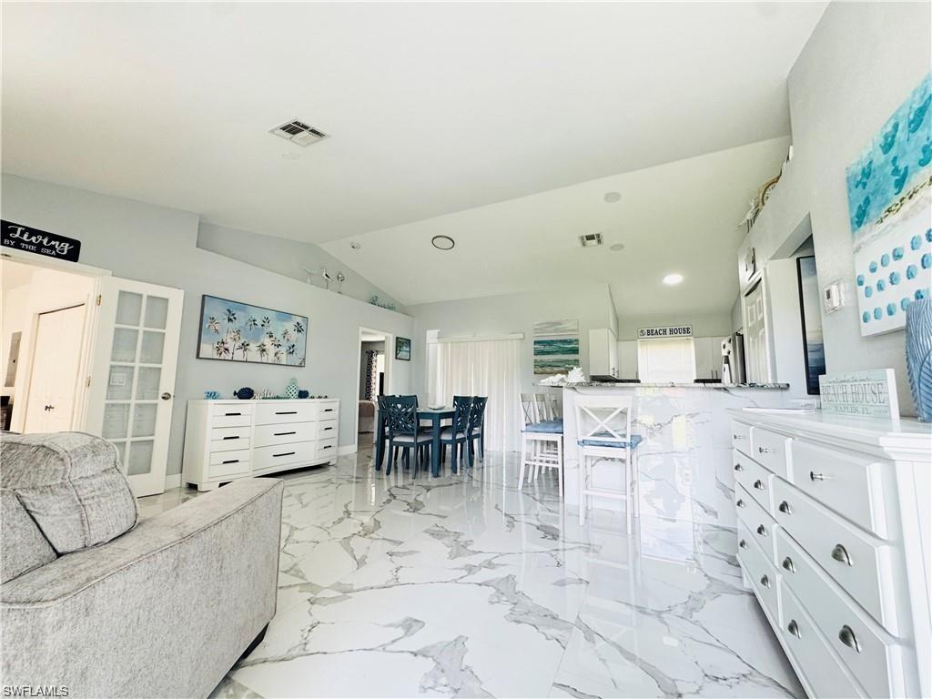 Living area featuring lofted ceiling and light marble finish flooring