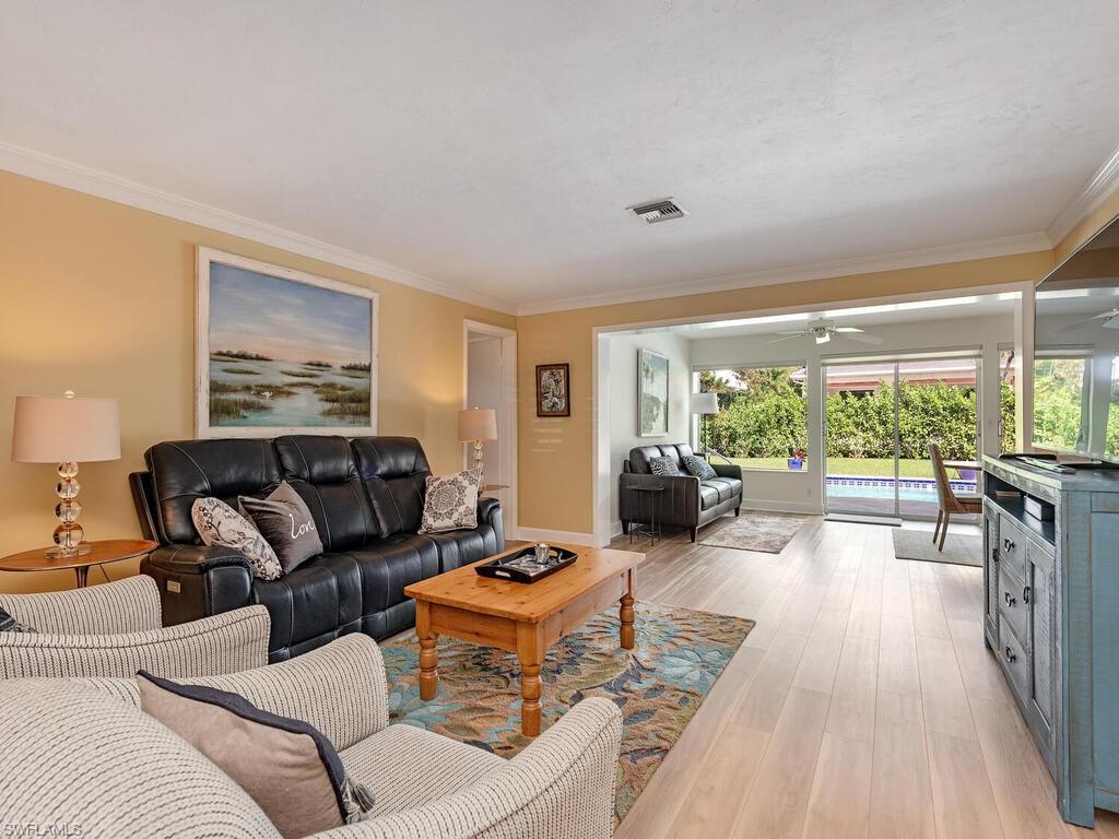 Living area featuring crown molding, ceiling fan, visible vents, and light wood finished floors