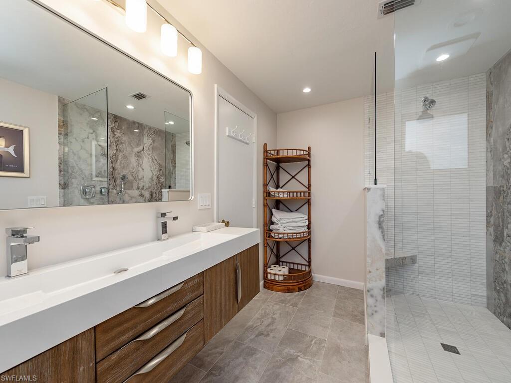 Bathroom featuring visible vents, double vanity, and walk in shower