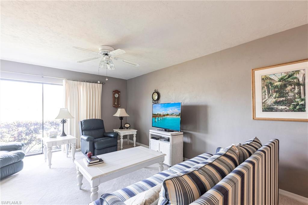 Living area featuring carpet floors, ceiling fan, and a textured ceiling