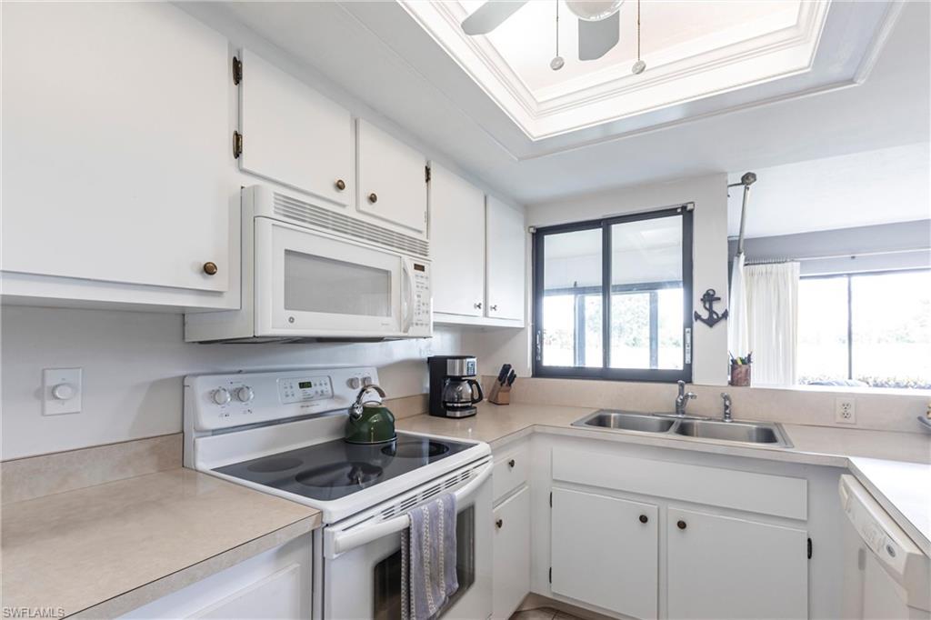Kitchen featuring newer white appliances, white cabinets, light countertops, and ornamental molding