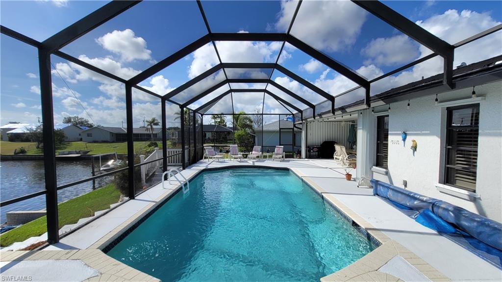 Outdoor pool featuring enclosure, a patio area, and a water view