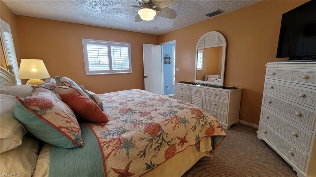 Bedroom with carpet, visible vents, a ceiling fan, a textured ceiling, and baseboards