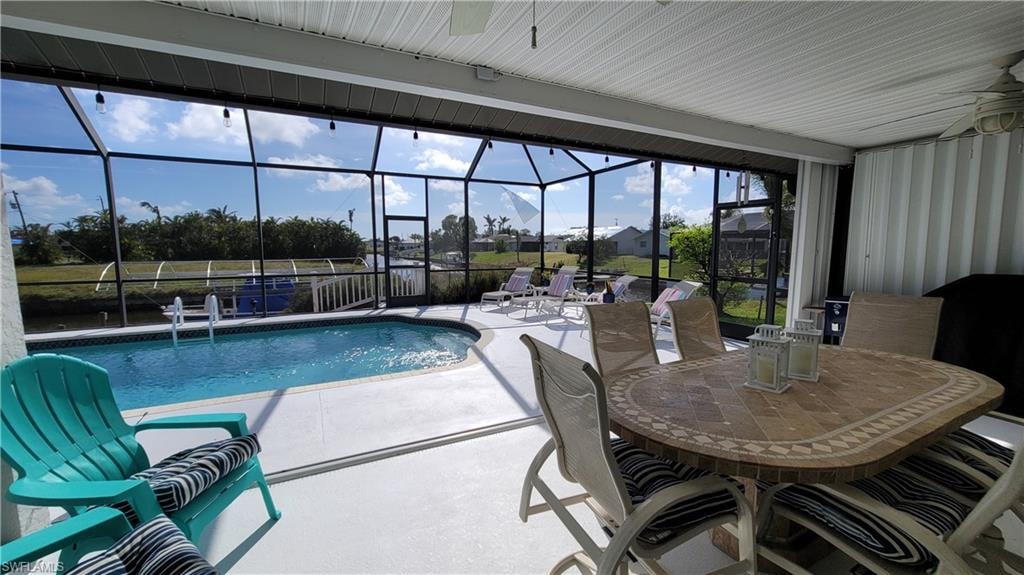 Pool featuring a lanai, a patio area, ceiling fan, and outdoor dining area