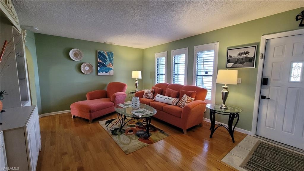 Living area with light wood-type flooring, a textured ceiling, and baseboards