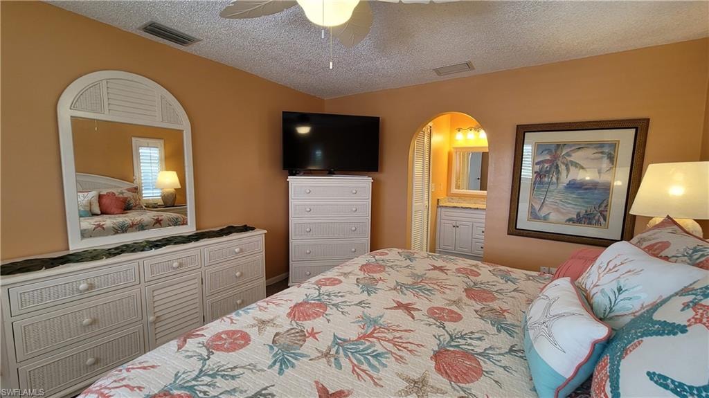 Bedroom featuring arched walkways, a textured ceiling, and visible vents