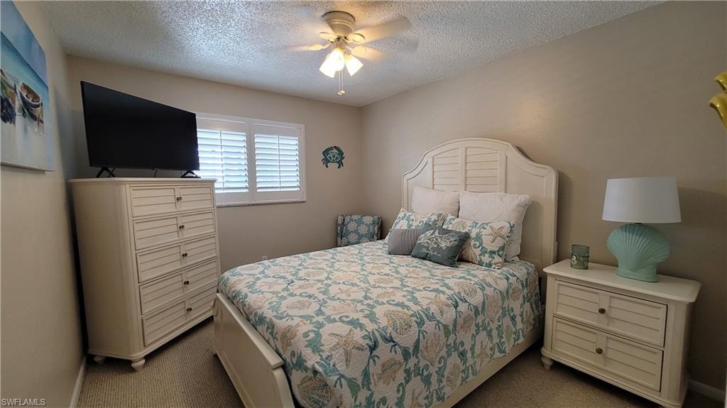 Bedroom featuring a ceiling fan, dark colored carpet, and a textured ceiling