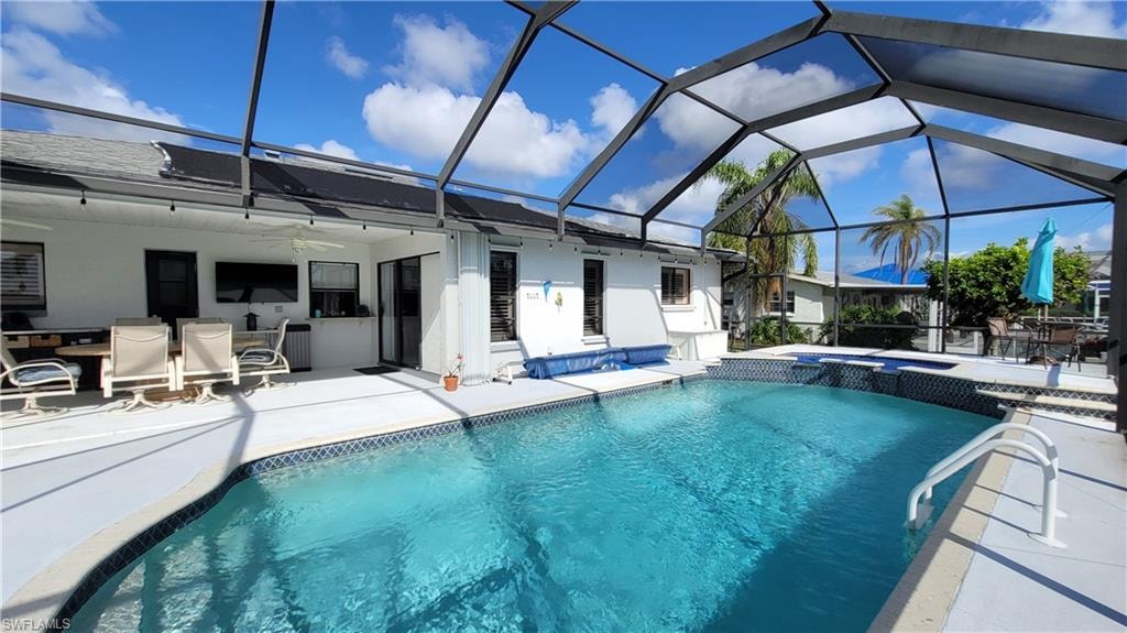 View of pool with ceiling fan, enclosure, a patio area, and a pool with connected hot tub
