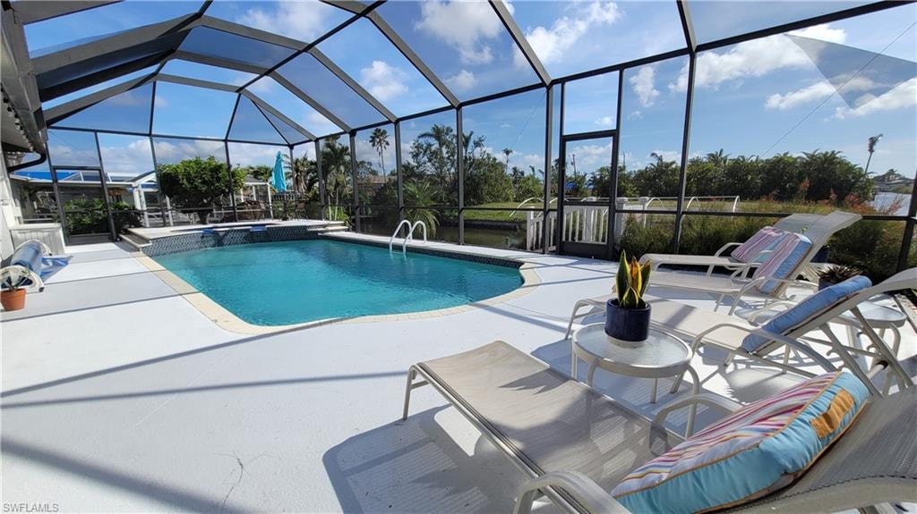 View of swimming pool featuring enclosure, a pool with connected hot tub, and a patio