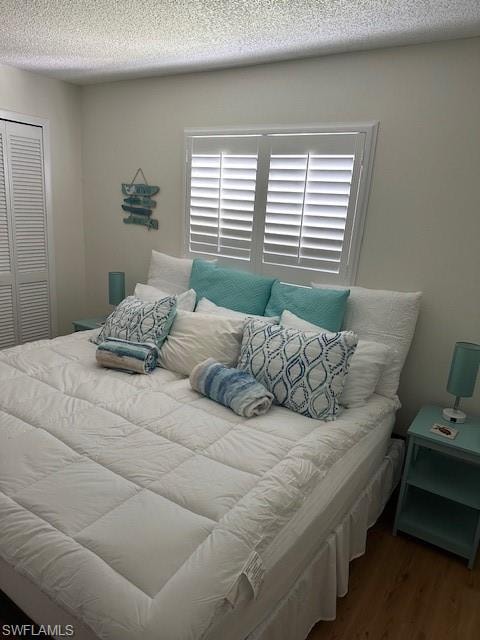 Bedroom with a textured ceiling, a closet, and wood finished floors