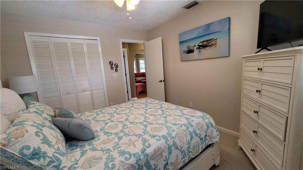 Bedroom featuring visible vents, arched walkways, a textured ceiling, carpet floors, and a closet