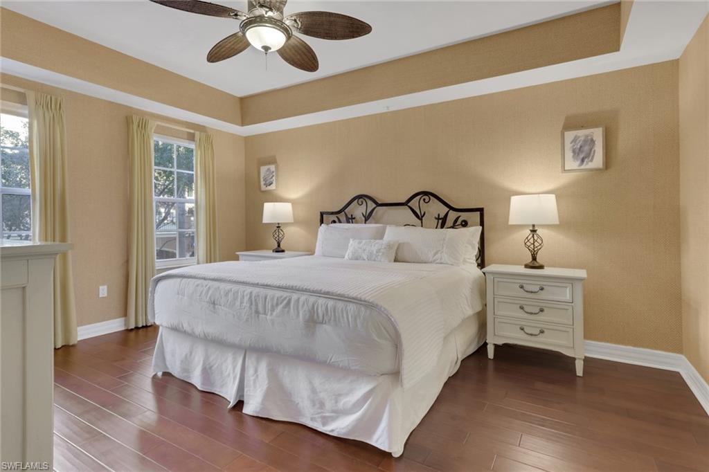 Bedroom with a ceiling fan, wood finished floors, and a tray ceiling