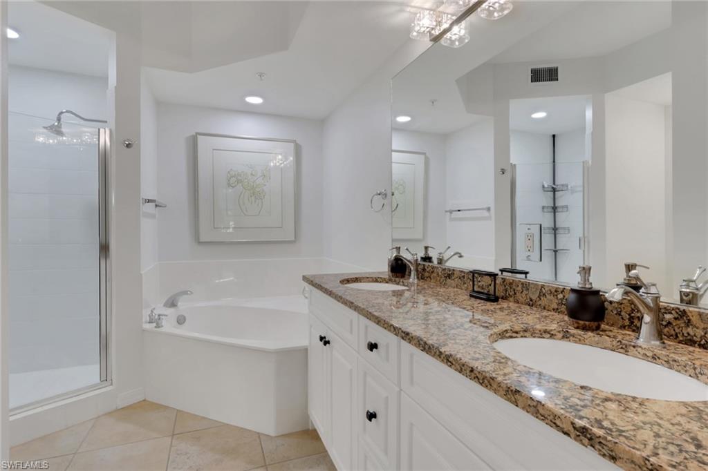 Full bath featuring double vanity, light tile patterned flooring, a shower stall, a bath, and recessed lighting