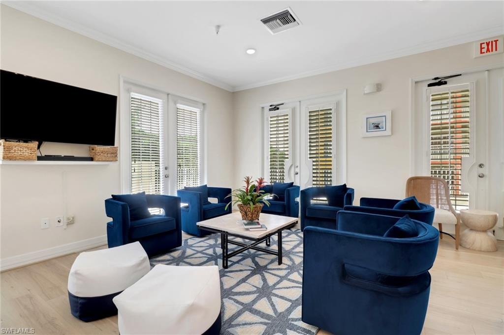 Living area featuring light wood-type flooring, ornamental molding, plenty of natural light, french doors, and recessed lighting