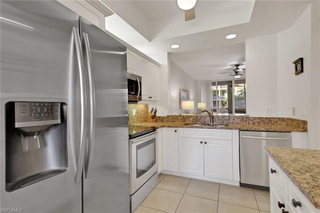 Kitchen with stainless steel appliances, recessed lighting, white cabinets, dark stone counters, and light tile patterned flooring