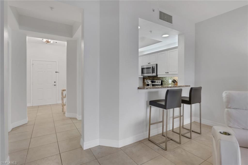 Hall featuring light tile patterned flooring and a tray ceiling