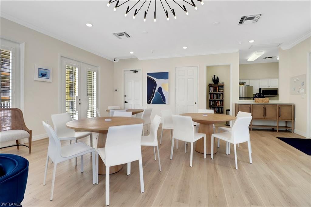 Dining space featuring crown molding, light wood-type flooring, recessed lighting, and french doors