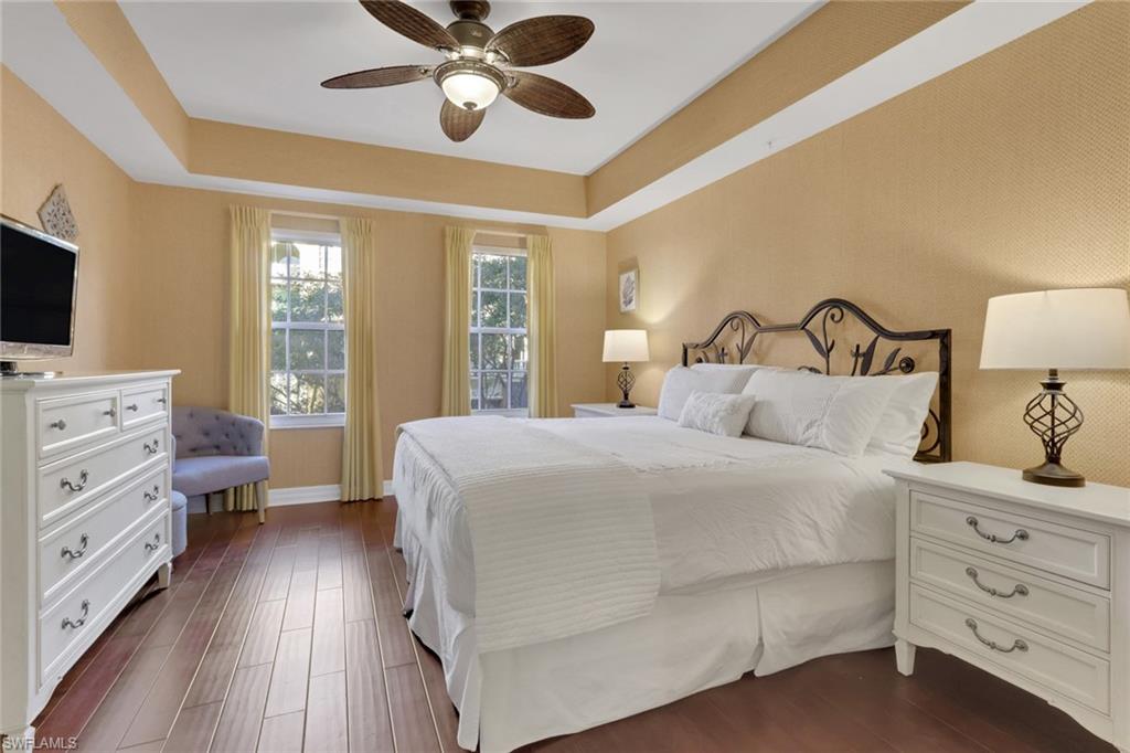 Bedroom featuring a tray ceiling, dark wood-style flooring, and ceiling fan