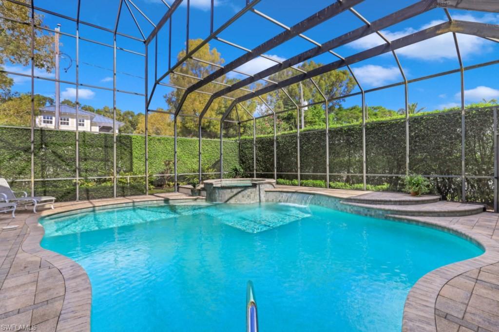 View of pool with fence, a lanai, a pool with connected hot tub, and a patio