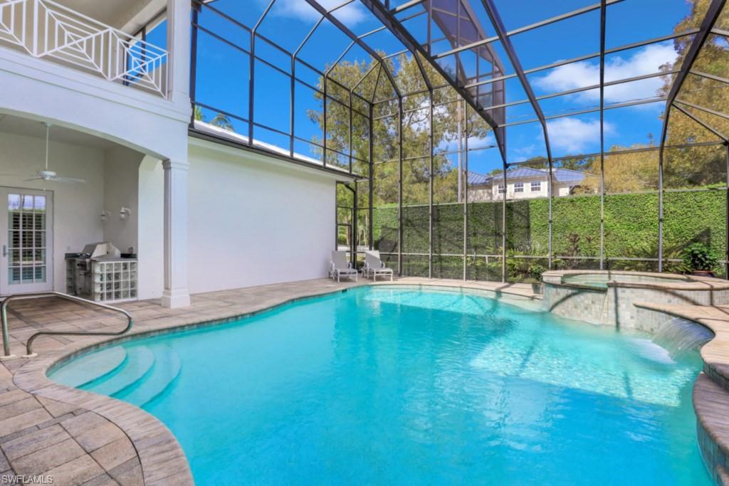 View of pool featuring ceiling fan, a pool with connected hot tub, a patio area, glass enclosure, and an outdoor kitchen