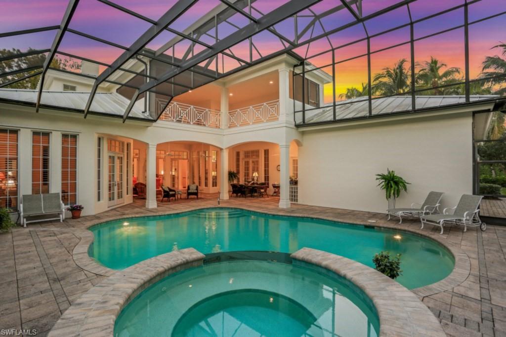 Pool at dusk with french doors, a lanai, a pool with connected hot tub, and a patio area