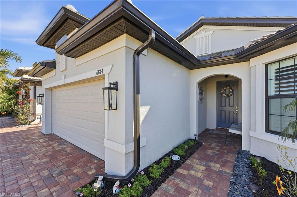 View of exterior entry featuring stucco siding, a garage, and driveway