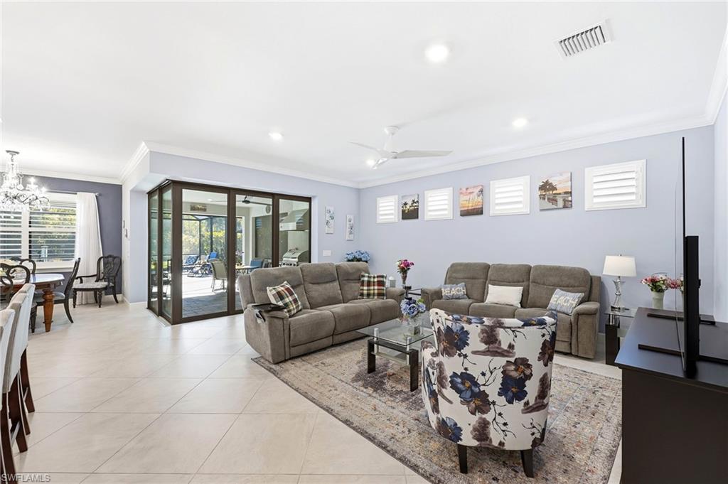 Living room featuring ornamental molding, healthy amount of natural light, light tile patterned floors, a ceiling fan, and suspended lighting